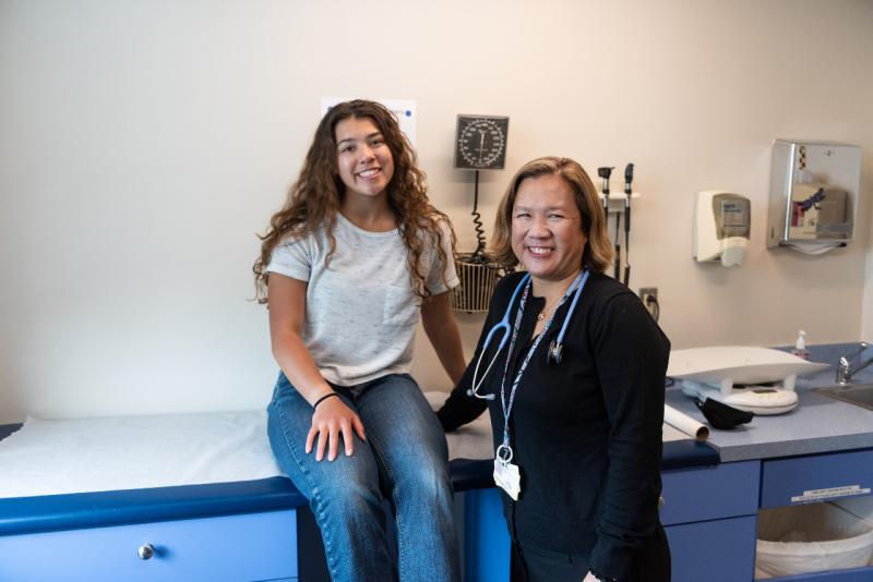 a teenage girl on an exam table next to a doctor